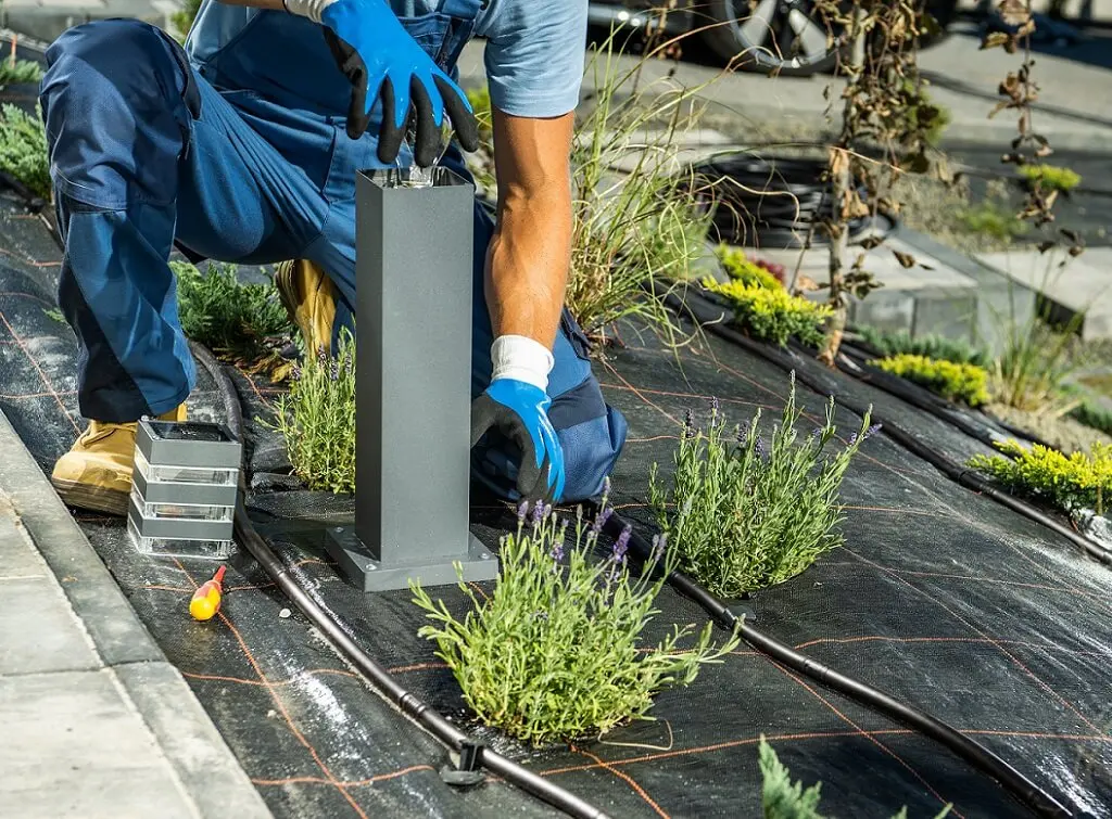 https://www.checkatrade.com/blog/wp-content/uploads/2024/10/outdoor-electrician-installing-light-fitting-in-garden-1.jpeg