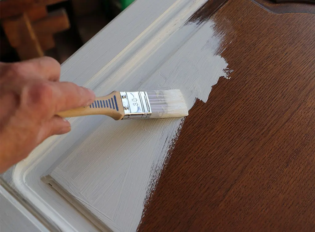 Primer being applied to a piece of dark wooden furniture ready for painting