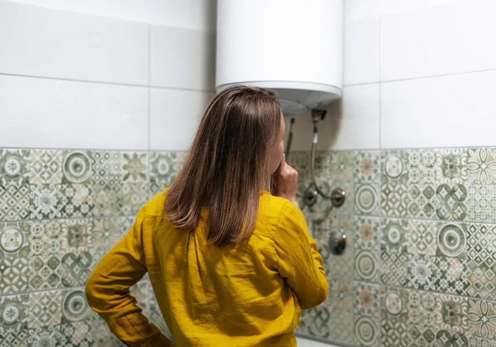 woman-inspecting-water-heater-bathroom