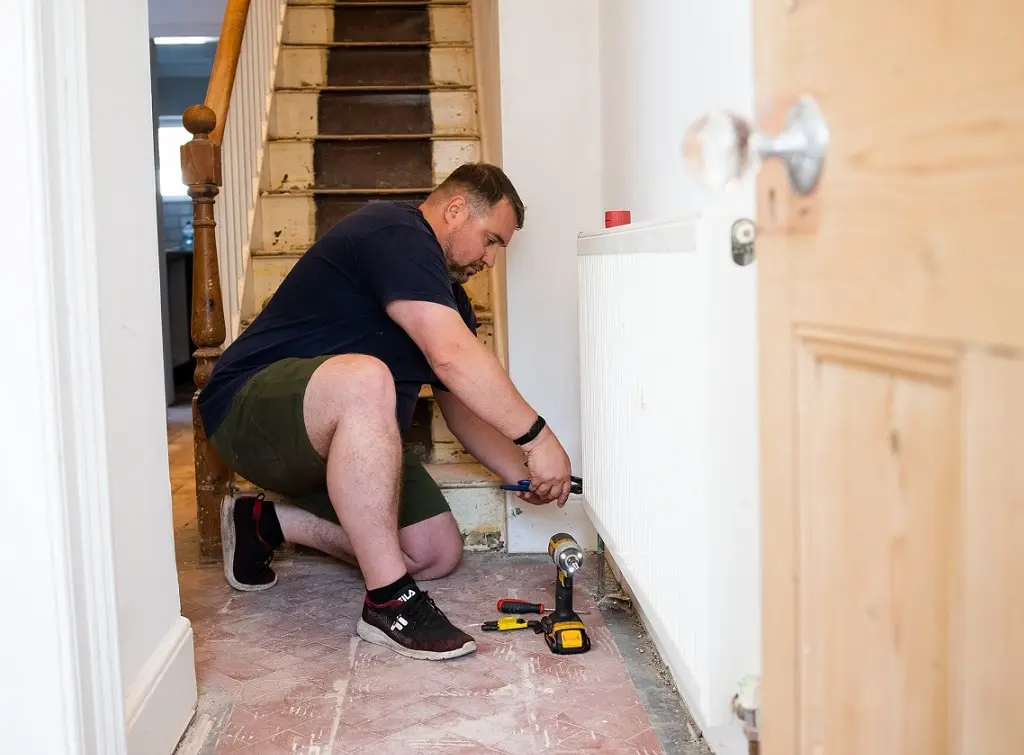 https://www.checkatrade.com/blog/wp-content/uploads/2024/08/handyman-draining-radiator-pipes.jpg