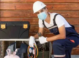 An air conditioner repair technician refilling Freon in a unit - Freon recharge cost