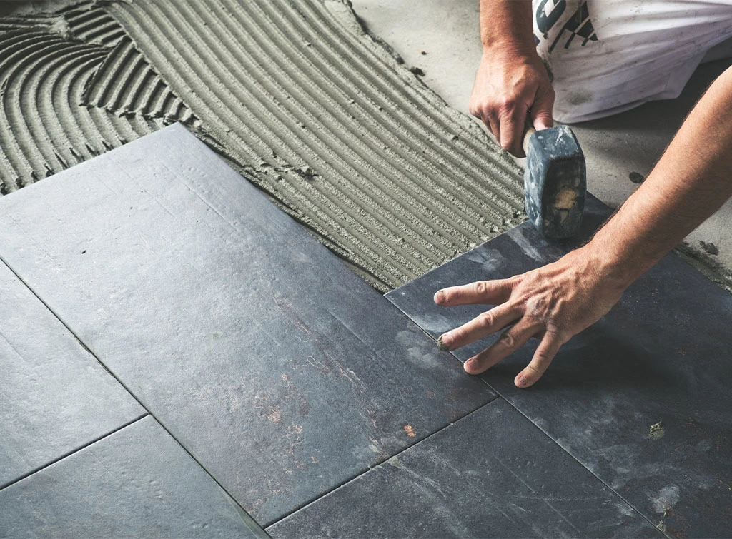 Tradesperson fixing floor tiles in blog: How to repair broken floor tiles