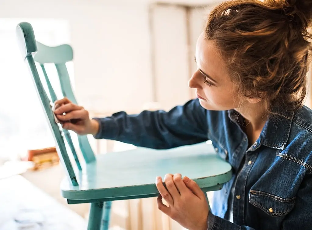 Woman refinishing a piece of wooden furniture