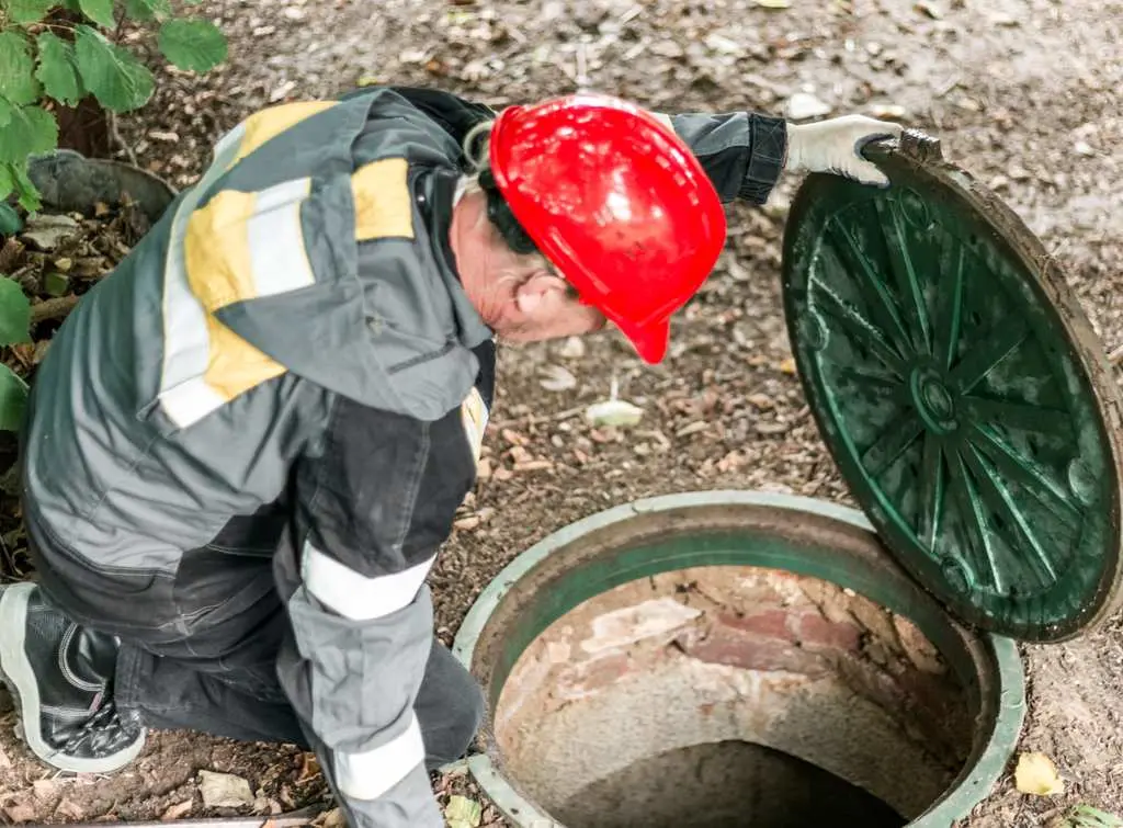 worker-in-hard-hat-opening-manhole-cover.jpg
