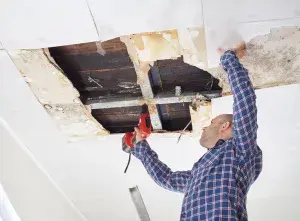 Tradesperson fixing severe ceiling damage