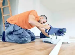 How to cut skirting board blog: Tradesperson on floor preparing the skirting board
