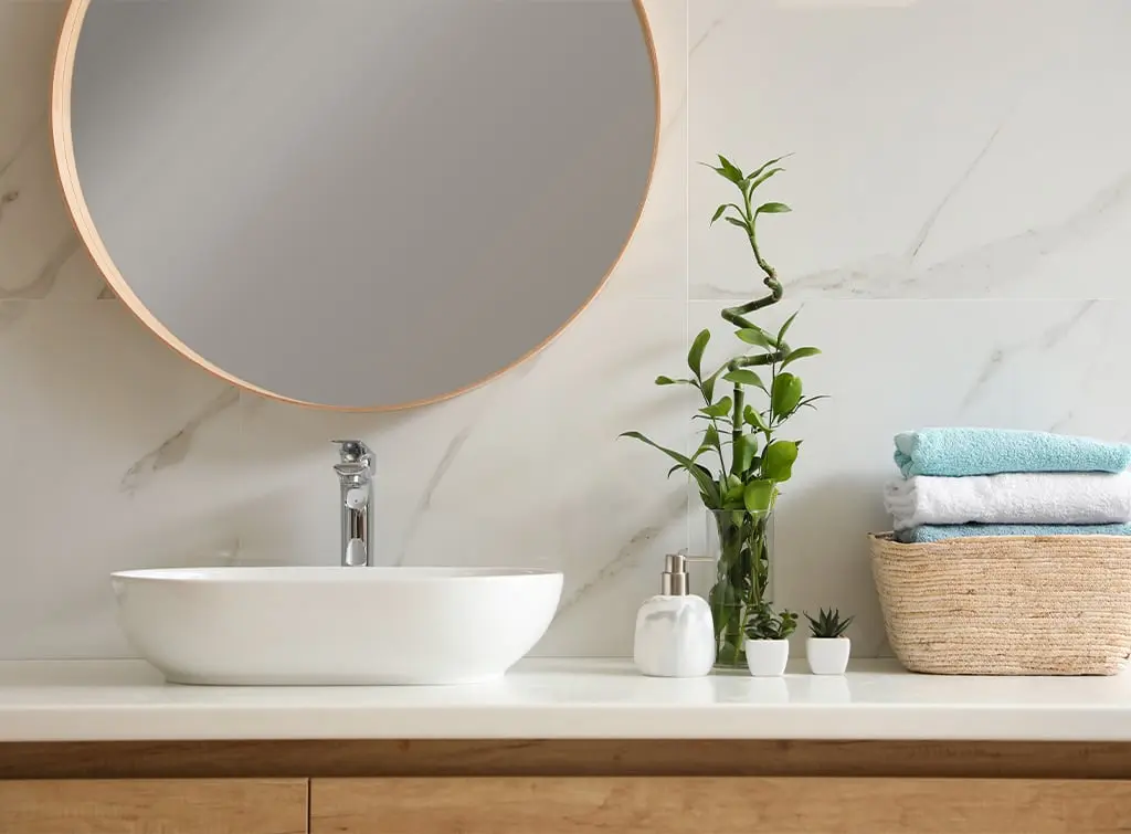 bathroom sink area with towels and plant