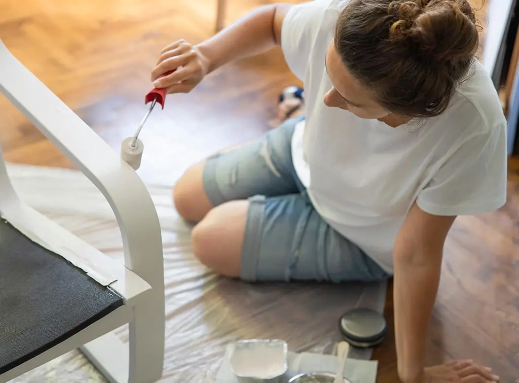 Woman painting a chair at home
