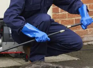 Man clearing a blocked drain using rods
