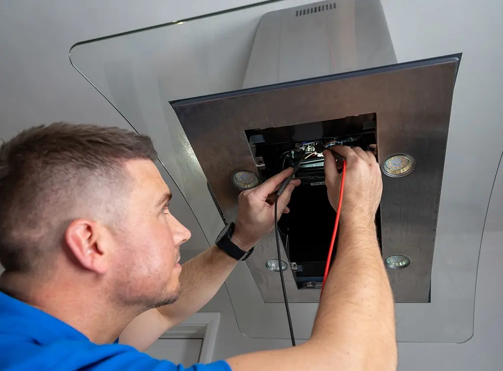 https://www.checkatrade.com/blog/wp-content/uploads/2024/07/electrician-fixing-extractor-fan.jpg