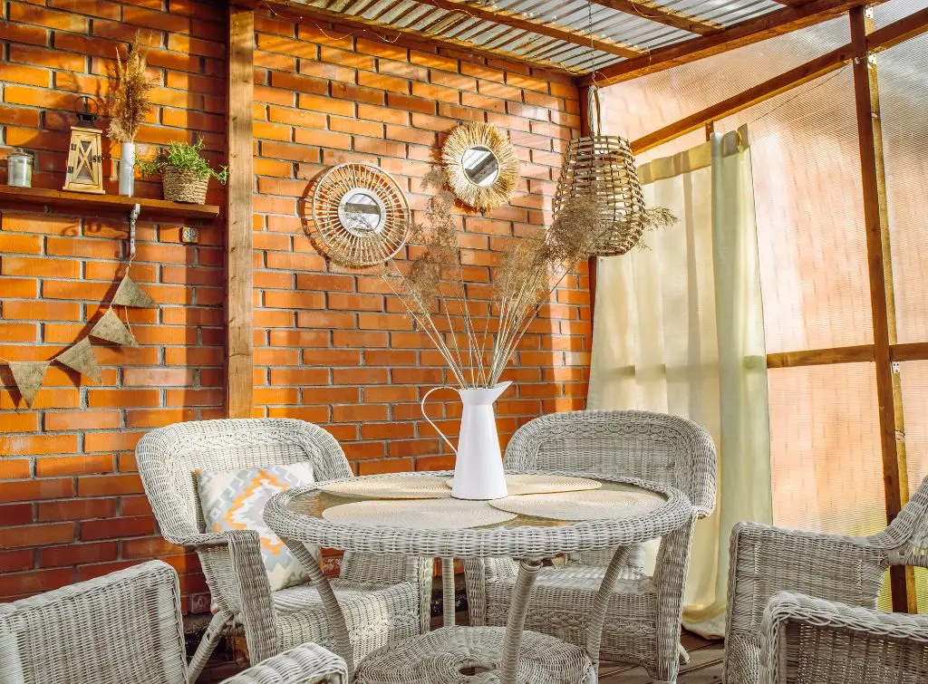 Rustic conservatory decor ideas – warm and homely vibes with brick wall and white rattan furniture