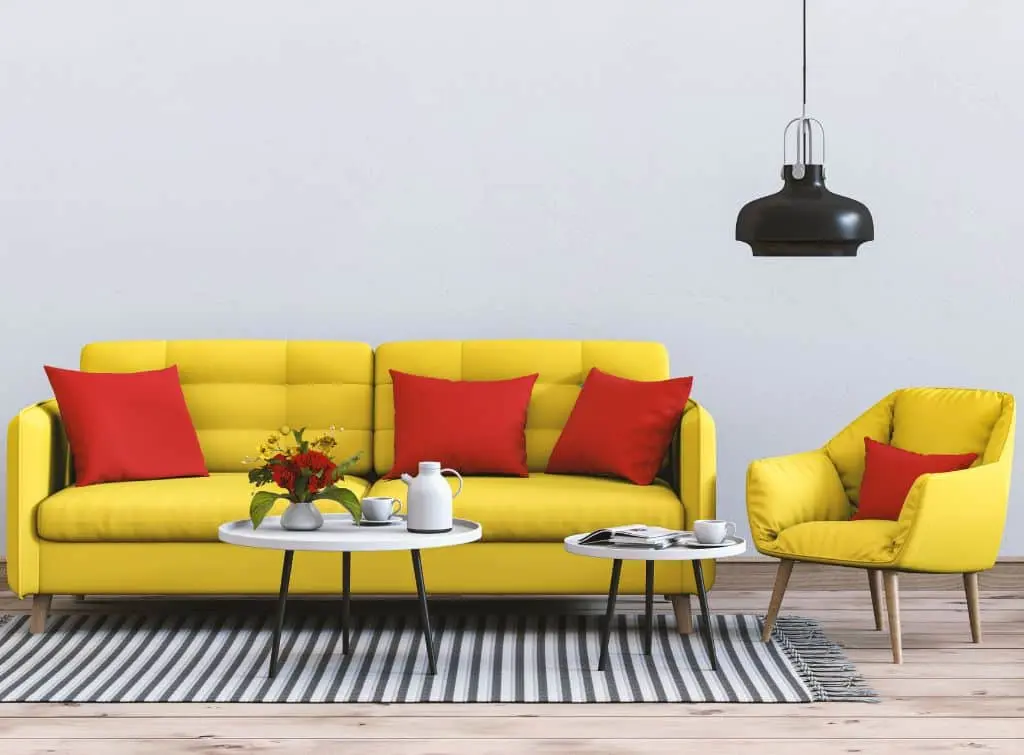 A yellow sofa with red cushions against a monochrome backdrop