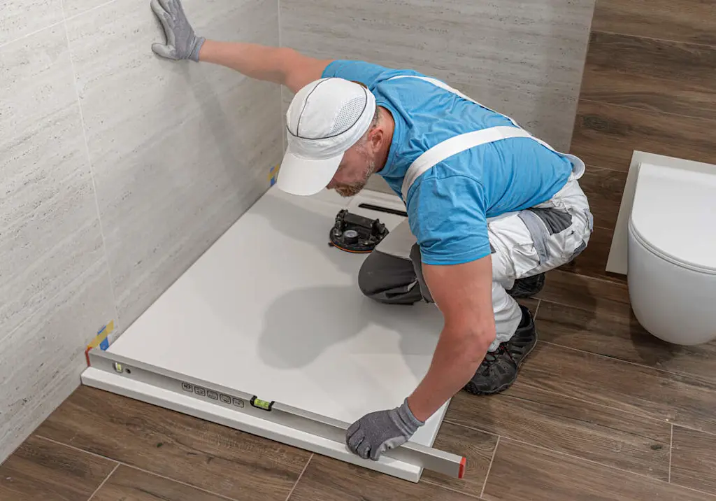 Plumber installing shower tray