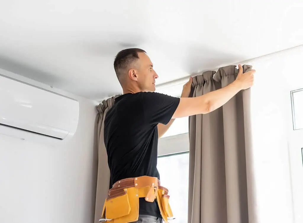 https://www.checkatrade.com/blog/wp-content/uploads/2025/03/tradesperson-hanging-new-curtain.jpeg