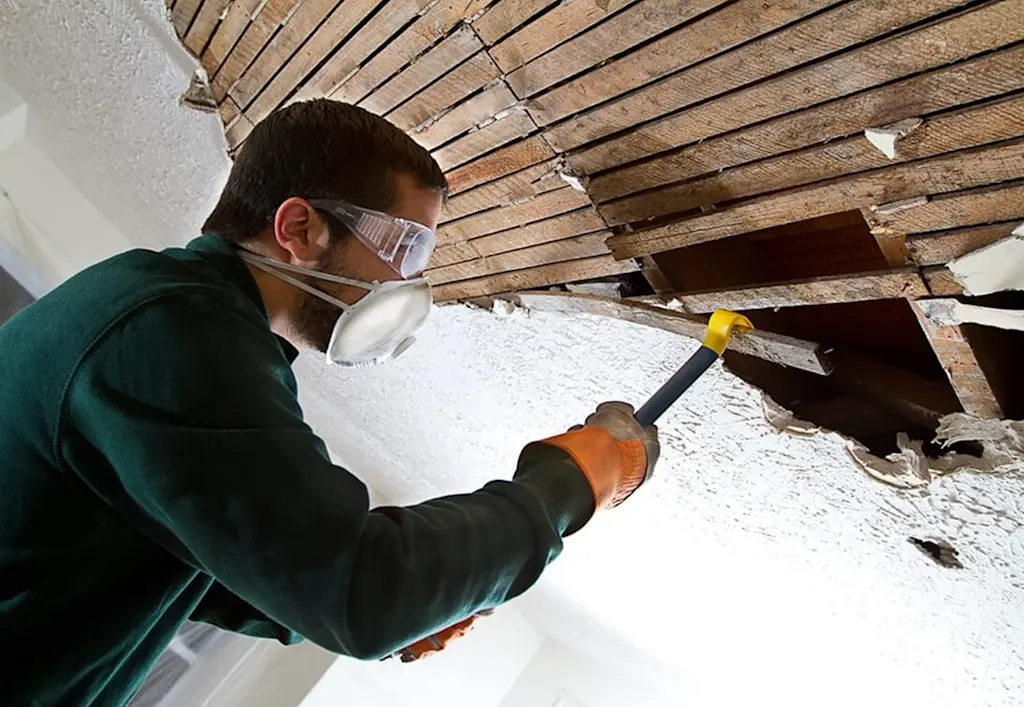 Man removing plaster lathe