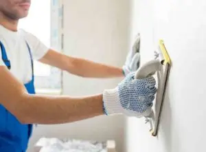 Builder plastering a wall -- flipping a house checklist