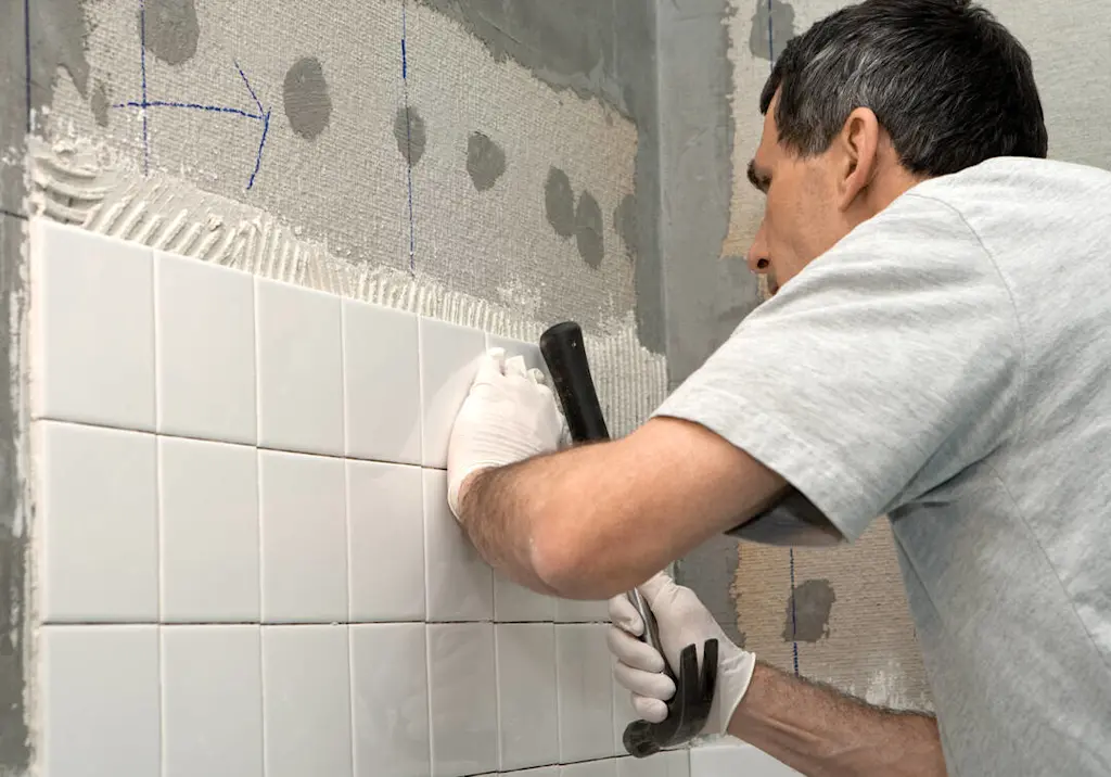 Tiler tapping wall tiles into place resized
