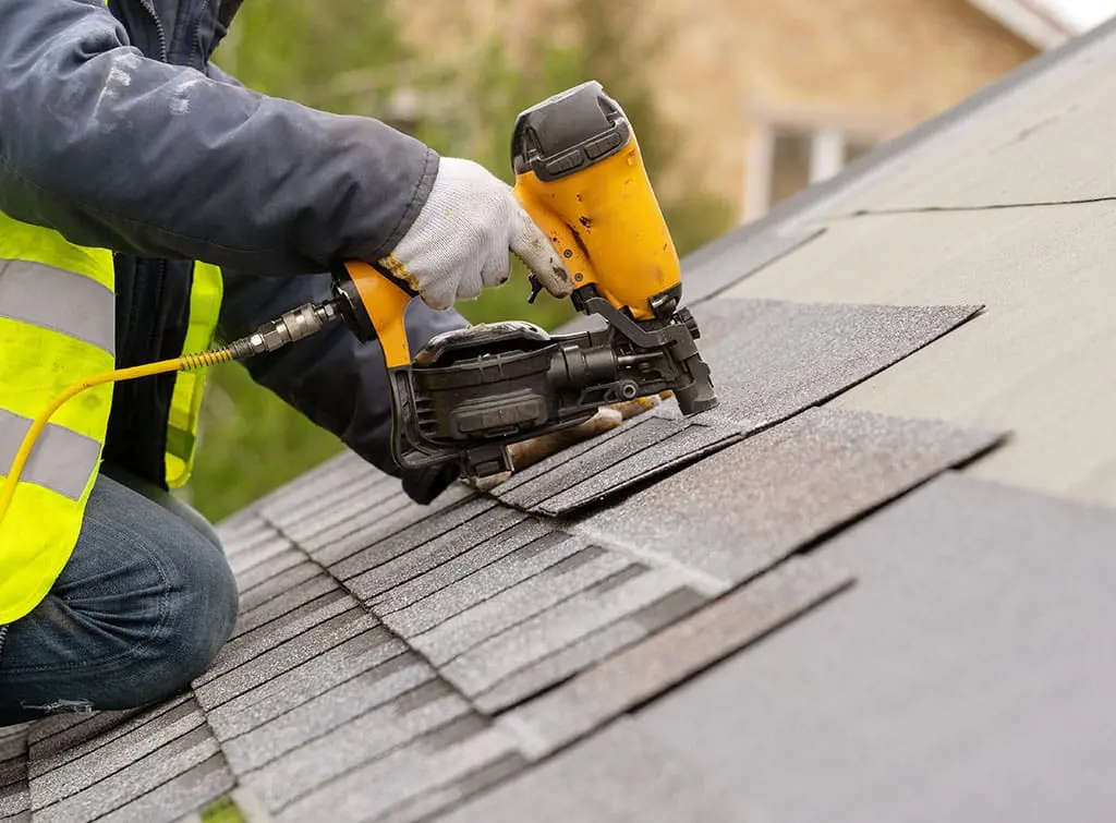 Felt roofers near me - Man holding nail gun on roof installing felt