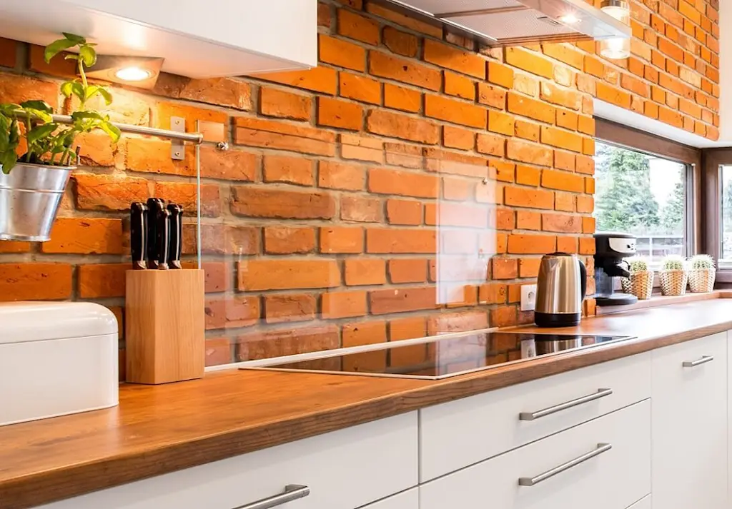 Glass splashback on brick wall