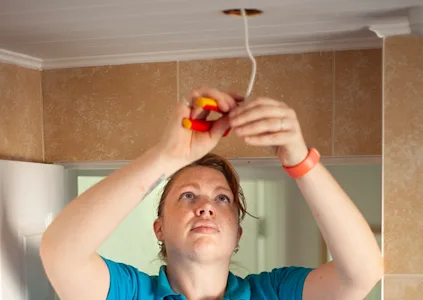 ANNE DUNCAN electrician working on light fitting