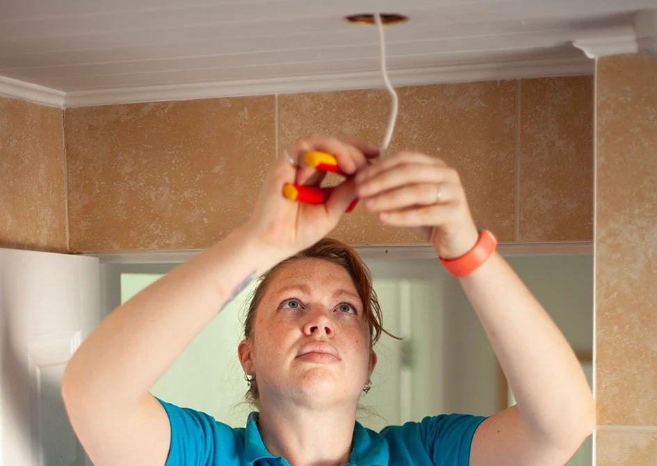 ANNE DUNCAN electrician working on light fitting