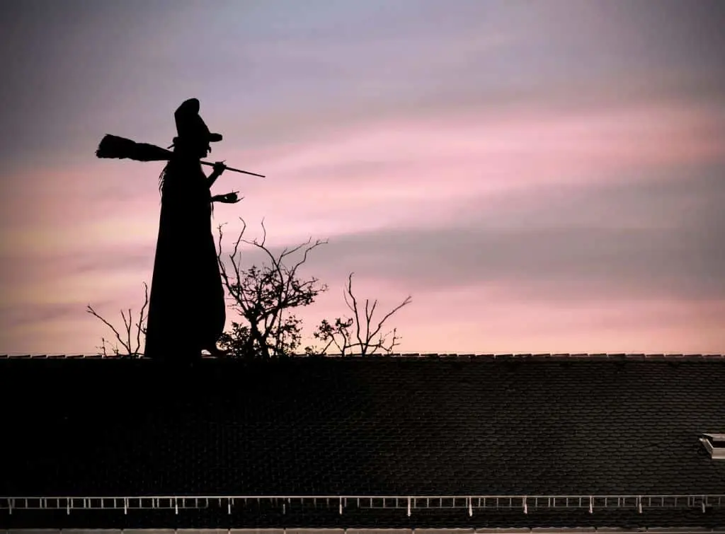 Witch walking on a roof at dawn - Halloween house ideas