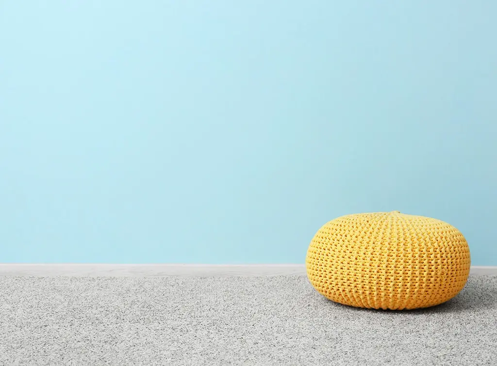 Carpet installation preparation - blue wall, grey carpet and yellow pouffe