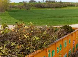 How to remove topsoil. Image: Skip with debris and garden waste in it.