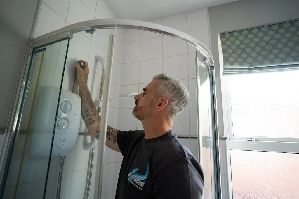 Tradesperson installing an electric shower in a quadrant shower enclosure