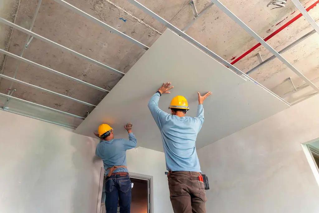 Two tradespeople replacing drywall on a ceiling for blog: How to repair a water damaged ceiling