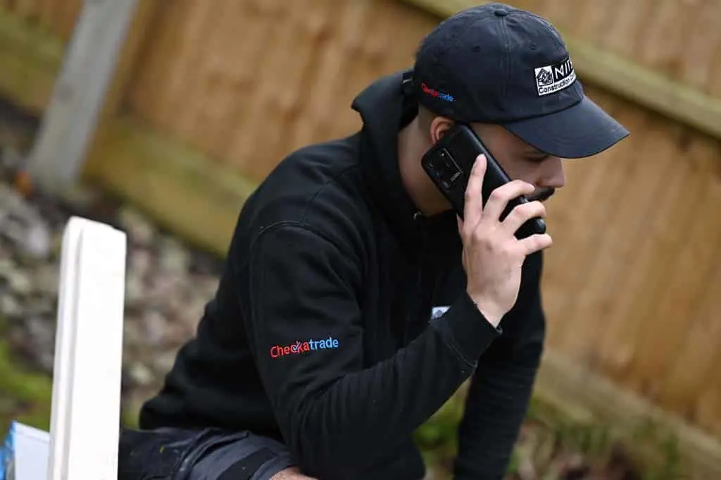https://www.checkatrade.com/blog/wp-content/uploads/2023/09/Tradesperson-using-mobile-phone.jpg
