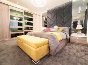 Brown bedroom carpet ideas with yellow storage trunk at the end of the bed