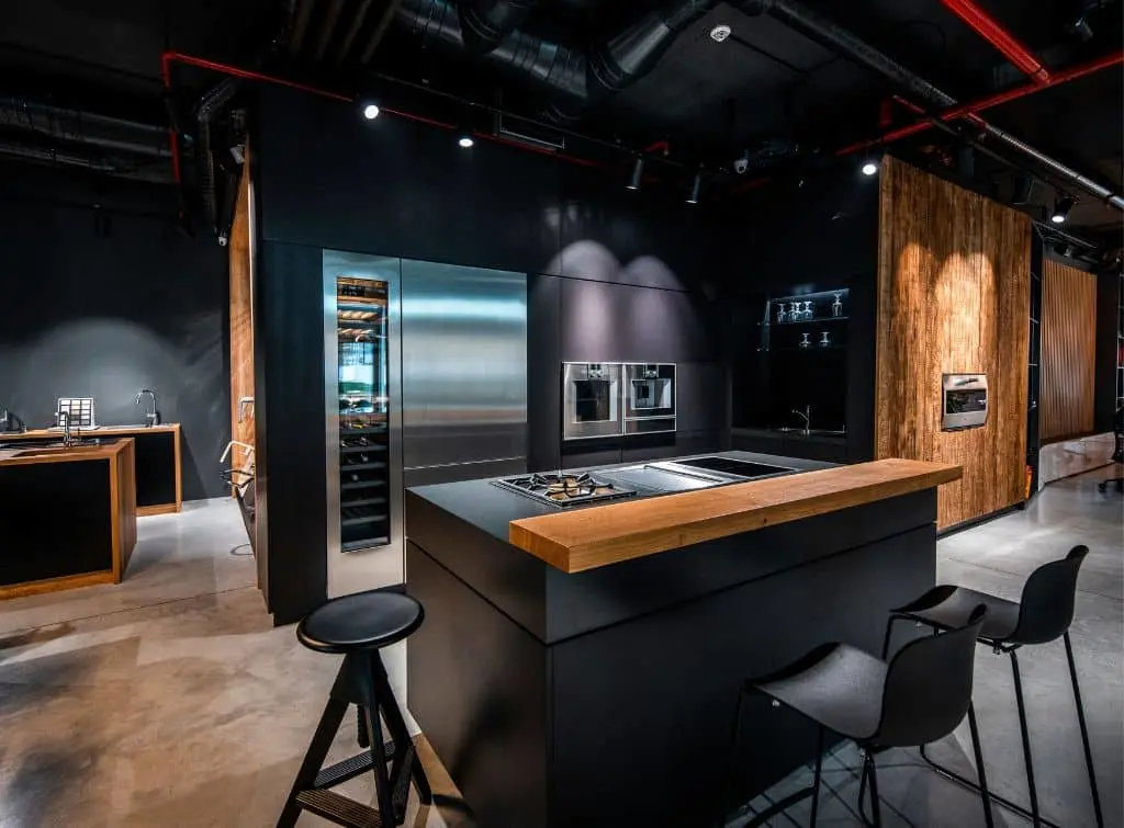 Black kitchen design with dark wood floors and chrome accessories