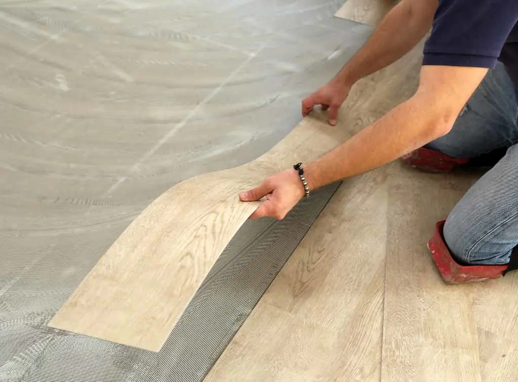 A floor fitter installing LVT flooring