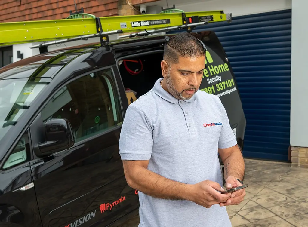 https://www.checkatrade.com/blog/wp-content/uploads/2023/06/Checkatrade-Safehome-Security-CheckingPhone.jpg