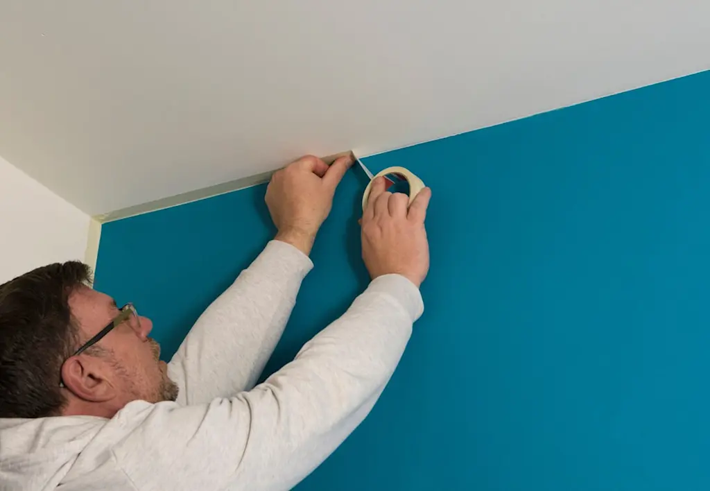 Applying masking tape to wall before painting