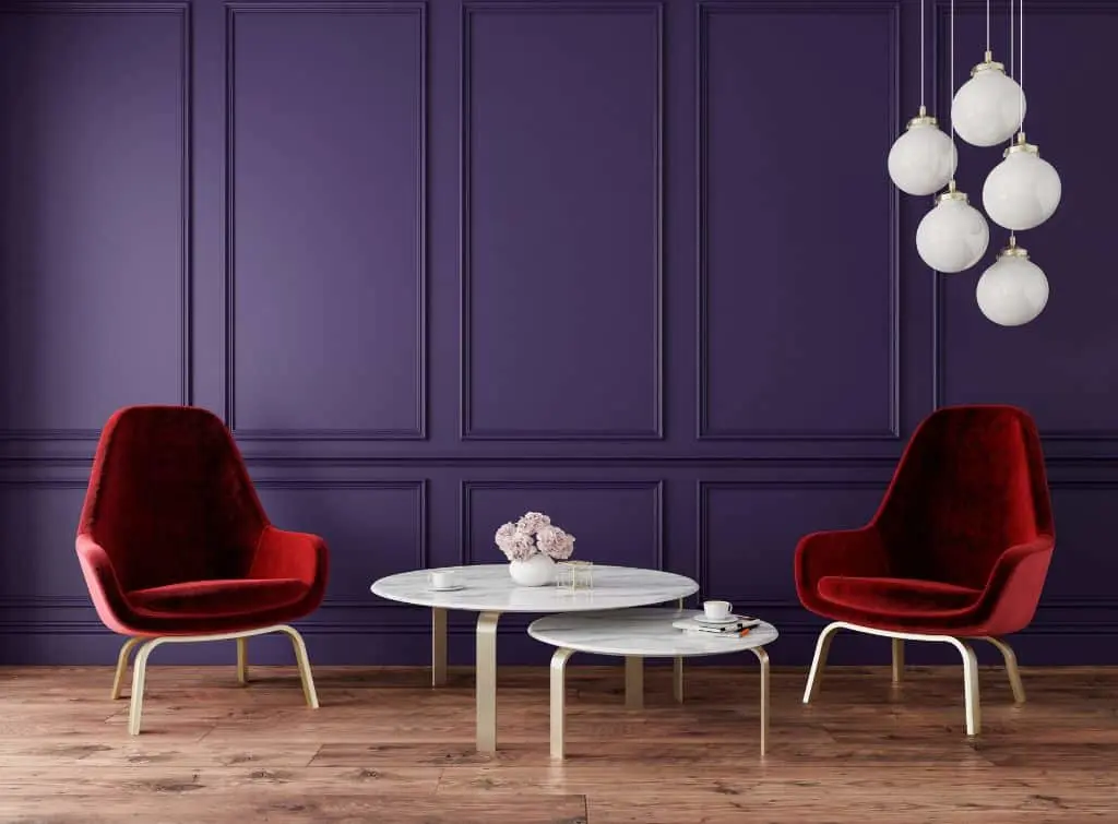 Purple panelled feature wall with blood red chairs around a stacked set of white coffee tables