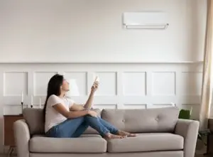 Woman using air conditioner from sofa