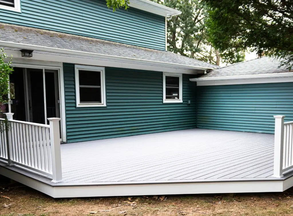 White decking stain with green wood panels on house in background