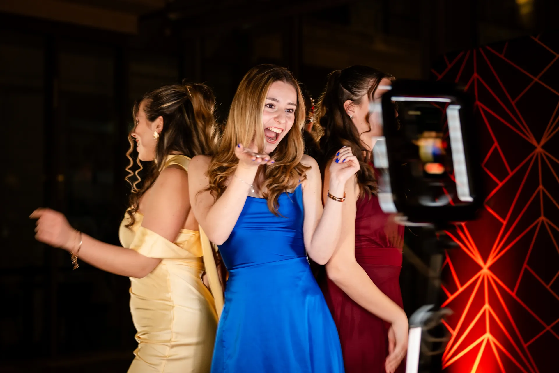 Vidám hölgyek pózolnak a körbeforgó kamera előtt egy bálon, élvezve a 360 fokos videót