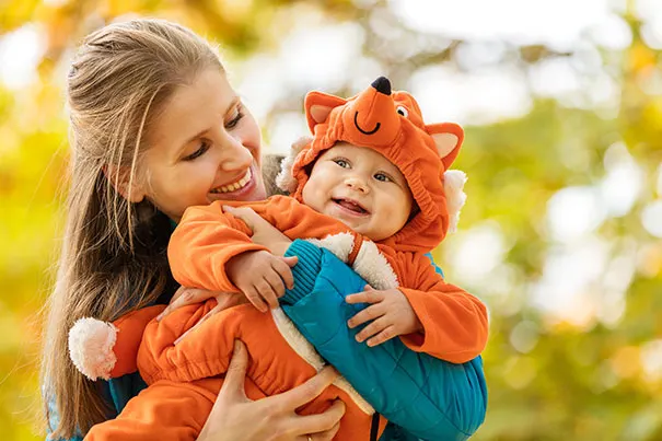 Mother holds baby in a fox baby carrier halloween costume 