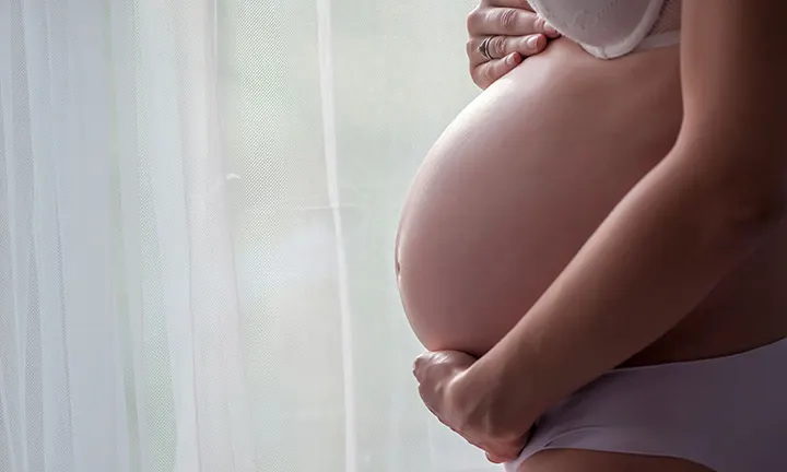 Pregnant woman holding her belly, representing the stage of pregnancy involving the mucus plug.