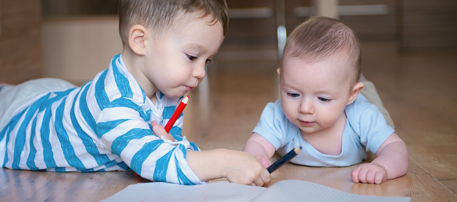 Toddler and baby drawing together