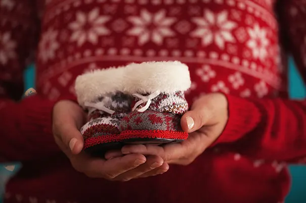 Mom holding a pair of babies’ Christmas boots