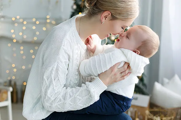 Mother holds baby in room decorated for Christmas