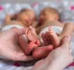 Parent holds the feet of newborn twins