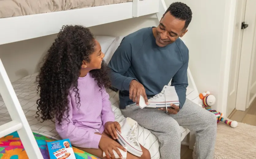 Un enfant et une personne assis sur le lit nettoyant des chaussures