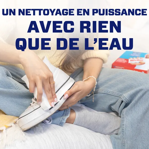 Une personne qui nettoie un soulier à l’aide d’un Effaceur magique M. Net et de l’eau