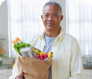 hombre sonriendo con compras de supermercado