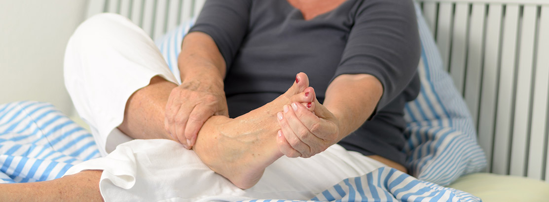 Old woman massages her cramped leg